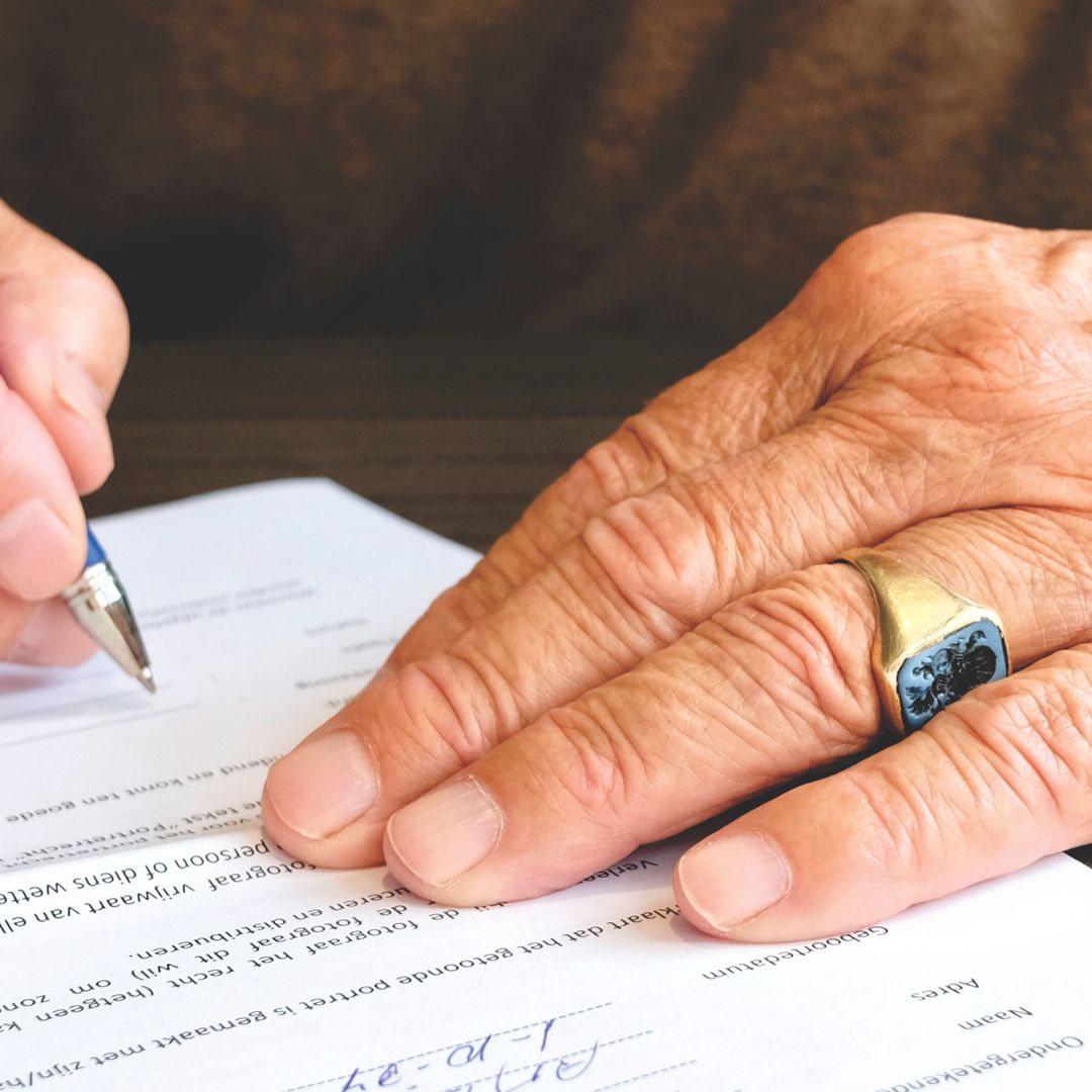 Close-up of a senior adult signing a legal document